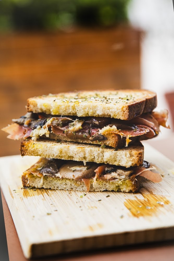 Tosta recheada de bacon e cogumelos colocada delicadamente uma em cima da outra